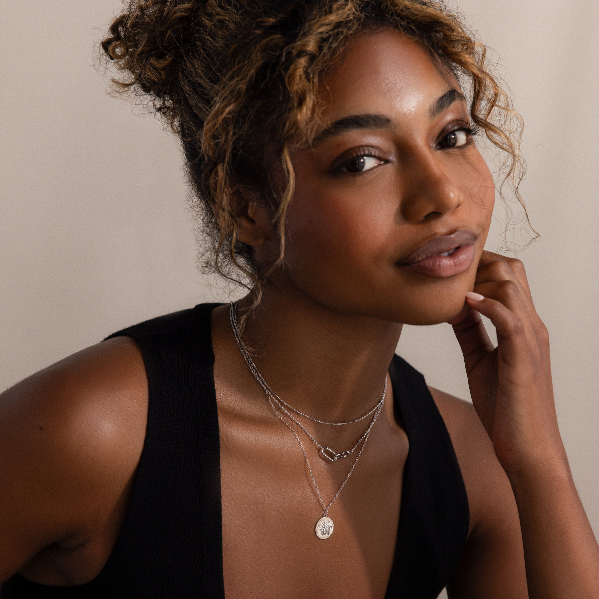 Smiling woman with curly hair wearing a black sleeveless top and the Linked Pendant Necklace in Silver, softly layered for a dainty look.
