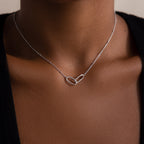 A close-up of the Linked Pendant Necklace in Silver, showcasing two interlocking links worn on a persons neck.