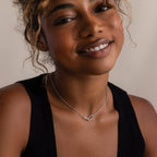 Woman smiling, wearing a black top and the Linked Pendant Necklace in Silver with a geometric design, against a neutral background.