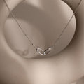 Linked Pendant Necklace featuring a heart-shaped linked pendant on a delicate chain, shown against a soft beige circular background.