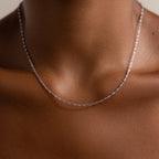 The Singapore Twist Necklace in Silver rests delicately on a person’s neck and upper chest, shining against smooth brown skin.