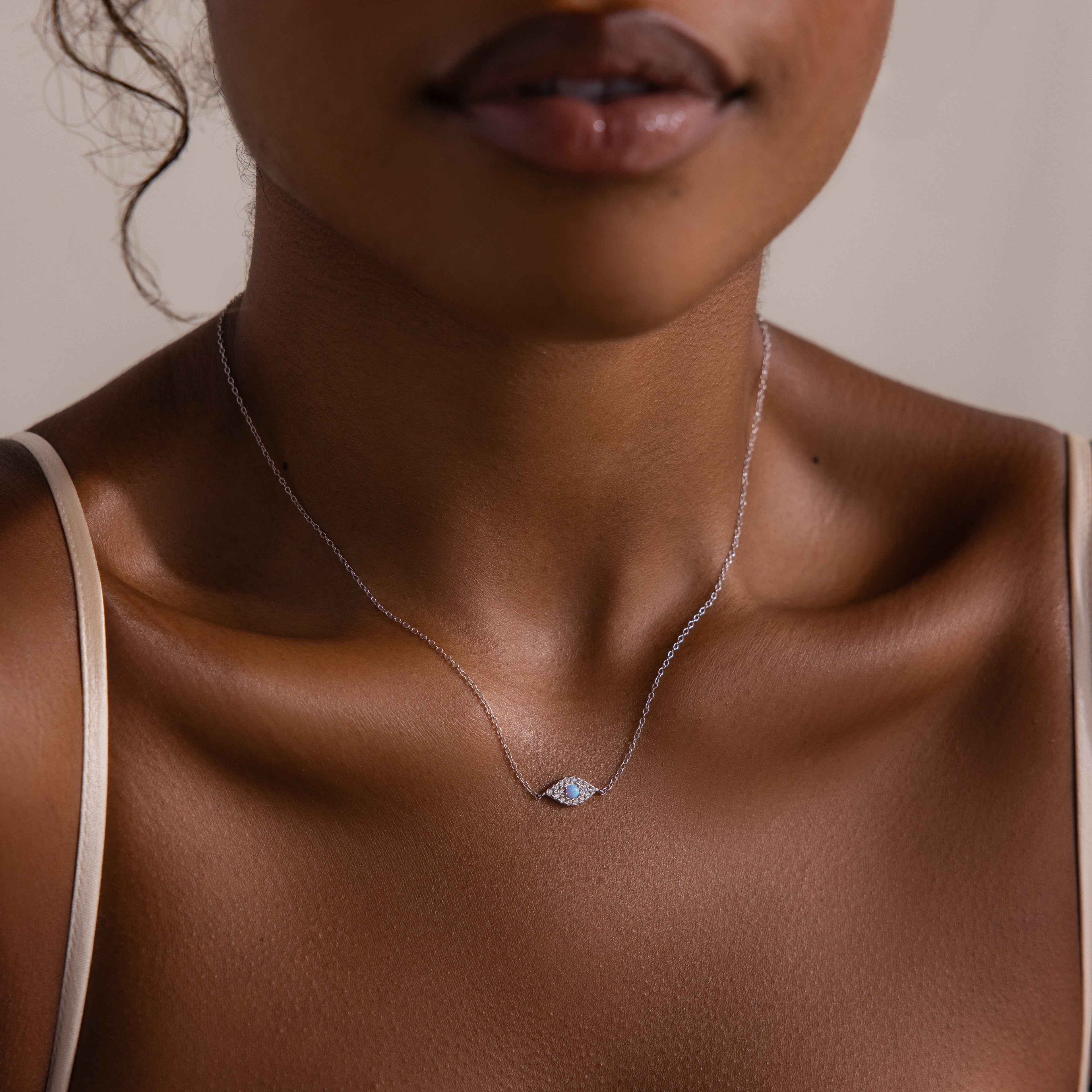 A woman, shown from shoulders to lips, wears the Opal Eye Necklace featuring an eye-shaped opal pendant.