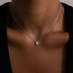 A close-up of a woman wearing the Rae Diamond Necklace in Silver, featuring a delicate chain and a small teardrop-shaped diamond pendant.