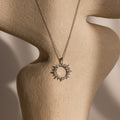 The Pave Sun Necklace in Silver, featuring sparkling pave accents, is displayed on a beige textured mannequin bust.