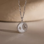 The Gabi Coin Necklace in Silver features a moon and star design with a beaded edge, adding minimal vintage charm—ideal for subtle style. Displayed on a neutral background.