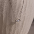 The Marquise Diamond Necklace in Silver features three leaf-shaped gemstones, embodying the elegance of fine diamond jewelry against a light textured fabric.