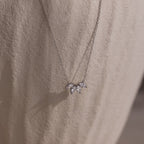 The Marquise Diamond Necklace in Silver features three leaf-shaped gemstones, embodying the elegance of fine diamond jewelry against a light textured fabric.