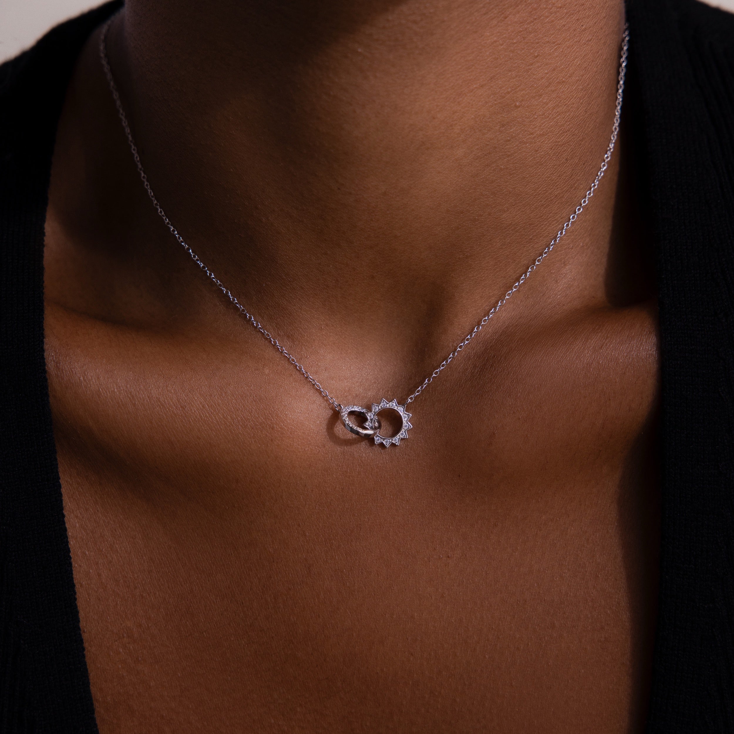 A close-up of the Sun  Moon Eternity Necklace in Silver, featuring two intertwined circles on a persons neck, highlights the delicate charm of this elegant piece.
