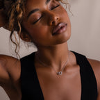 Woman with curly hair, eyes closed and head tilted back, wears a black top and the Sun  Moon Eternity Necklace in Silver.