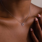 A close-up of a woman wearing the Forever Pave Heart Necklace in Silver, her hand gently touching her neck.