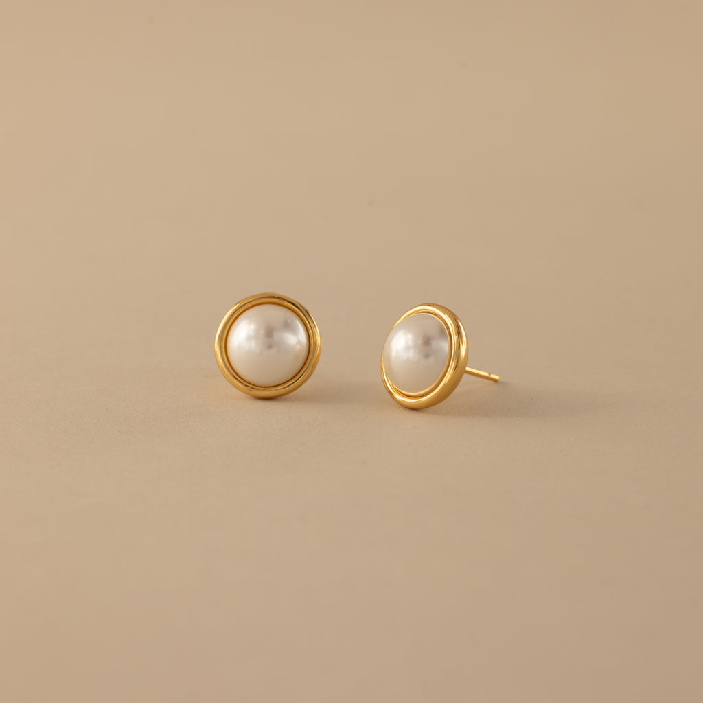 The Pearl Bezel Studs—gold stud earrings with round white pearls—add timeless elegance to any look, making them a perfect choice for every occasion.