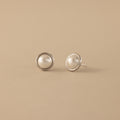 Pearl Bezel Studs in Sterling Silver displayed on a beige background.