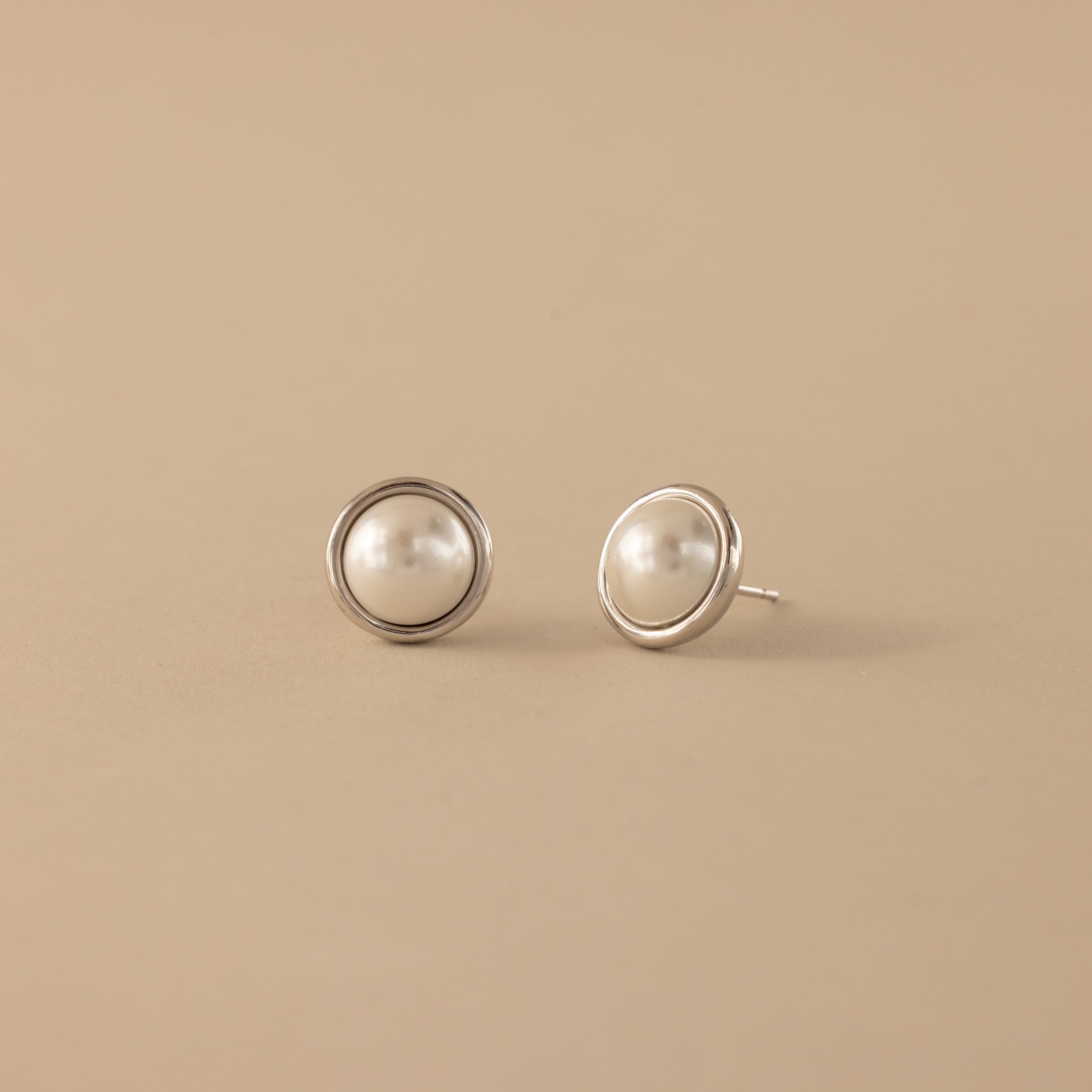 Pearl Bezel Studs in Sterling Silver displayed on a beige background.