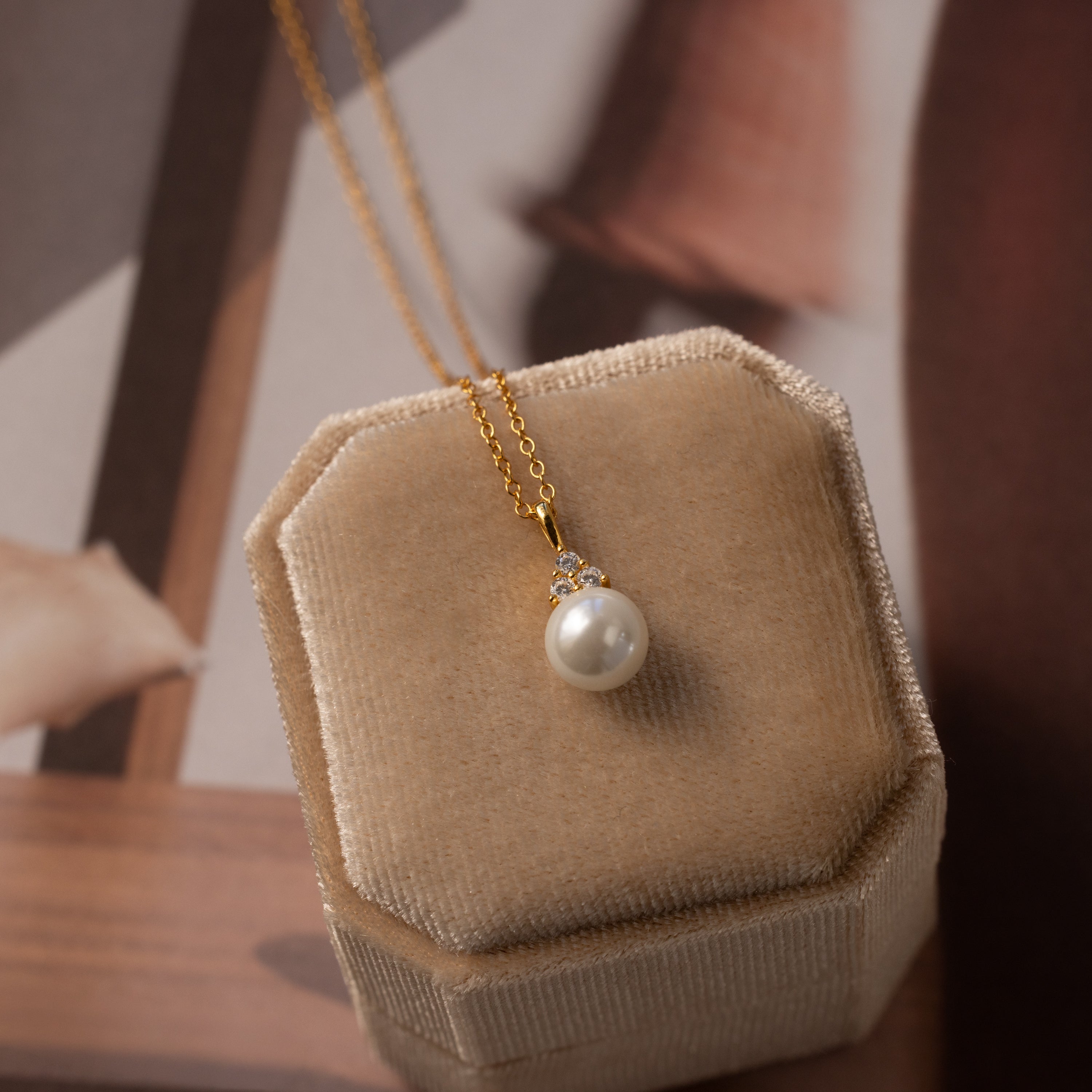 The Diamond Halo Pearl Necklace features a delicate pendant and sparkling crystals, presented in a beige velvet jewelry box—a timeless accessory perfect for any occasion.