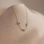 Dainty silver bubble letter necklace with the initials "MDH" displayed on a neutral surface.