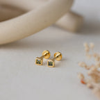 Square Bezel Peridot Flatback Studs: Small gold square stud earrings with vibrant peridot CZ gemstones, shown on a neutral background. Perfect for adding a pop of color to any look.