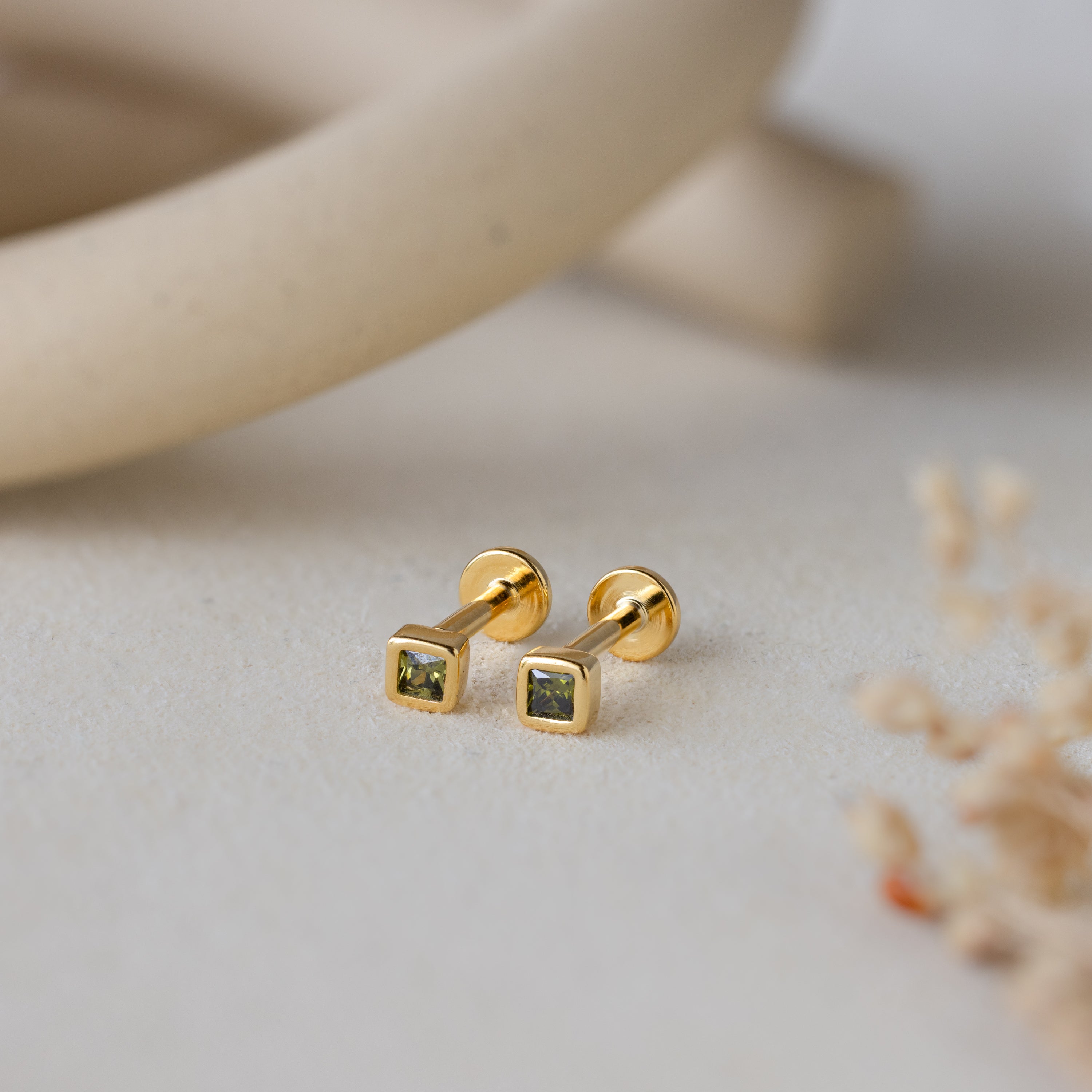 Square Bezel Peridot Flatback Studs: Small gold square stud earrings with vibrant peridot CZ gemstones, shown on a neutral background. Perfect for adding a pop of color to any look.