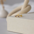 Square Bezel Amethyst Flatback Studs are shown on a beige textured surface, highlighting their classic look.