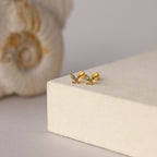 Butterfly Peridot Flatback Studs shown on a light beige surface with a seashell—ideal as a personalized gift or stylish flat back earrings for everyday elegance.