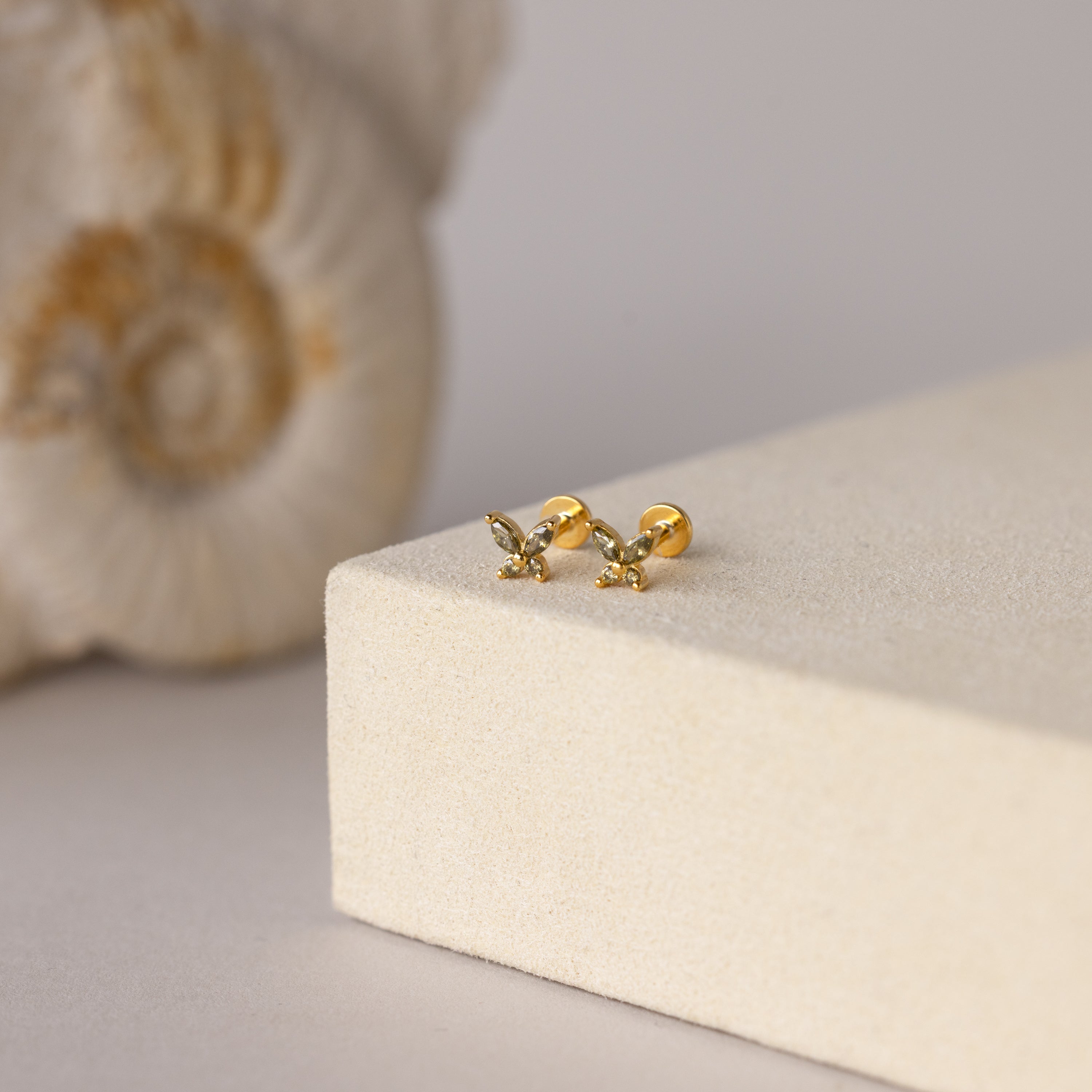 Butterfly Peridot Flatback Studs shown on a light beige surface with a seashell—ideal as a personalized gift or stylish flat back earrings for everyday elegance.