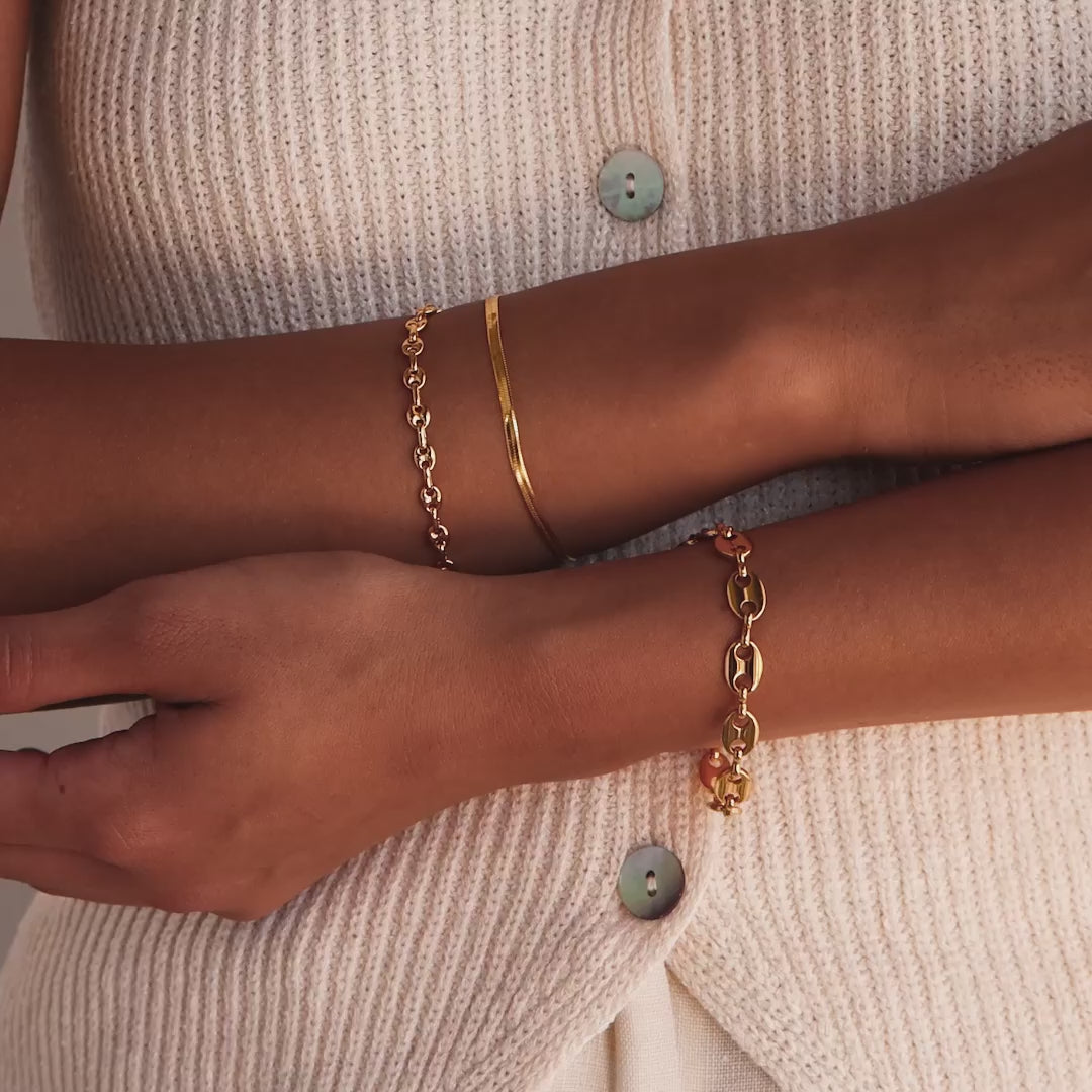 Model showcasing the Mini Mariner Chain Bracelet in gold, stacked with a larger mariner chain bracelet and a herringbone bracelet.