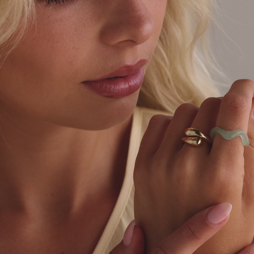 Model showcasing the Jade Wave Ring featuring a curved silhouette carved from natural green jade, styled with a gold duo dome ring.