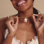 Model wears a gold rolo clasp necklace with multiple different pearl charms dangling from it 