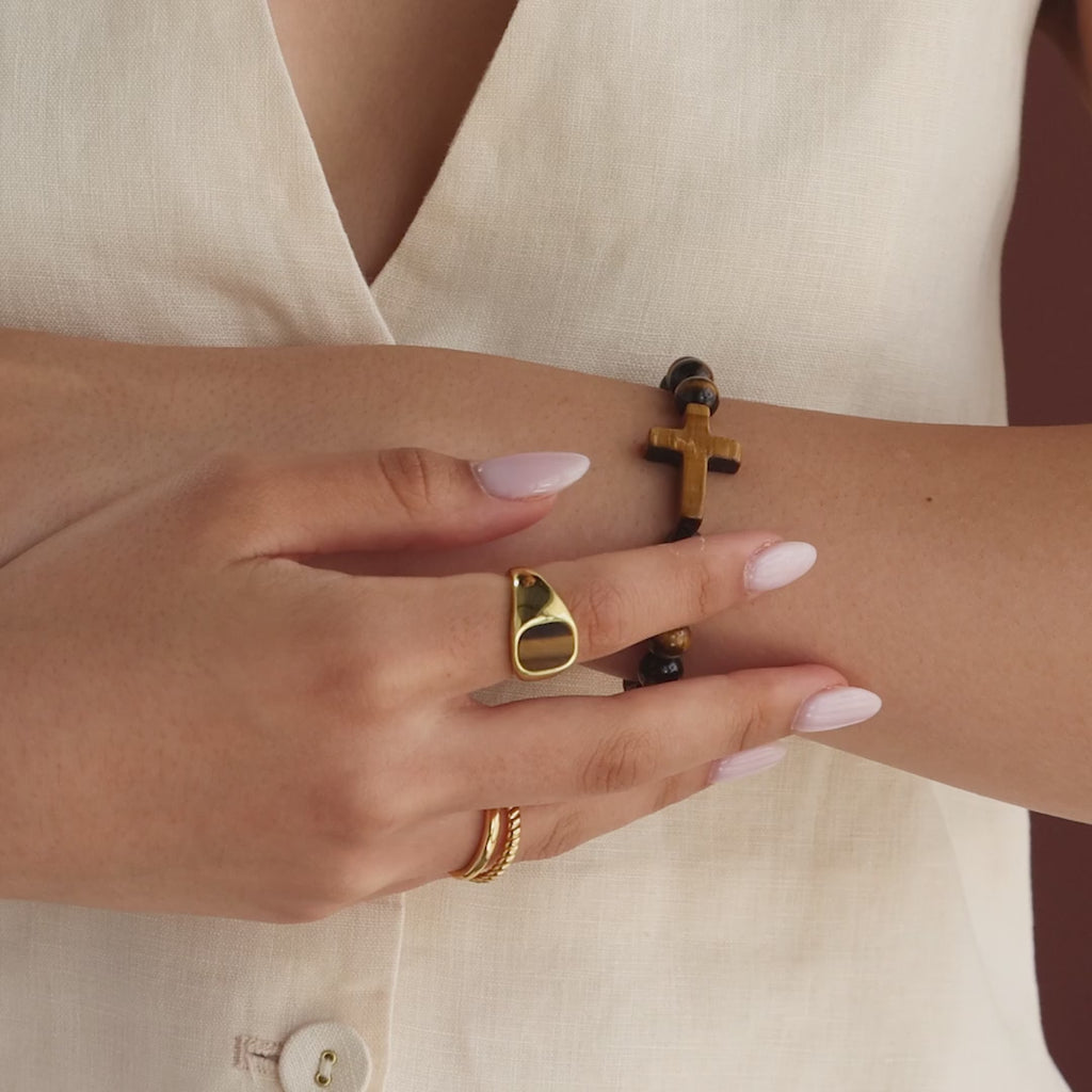 Model showcasing the Tigers Eye Cross Bracelet, styled with a gold tigers eye signet ring and gold duo band ring.
