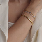 Model wearing Mixed Metal Star Bracelet, layered with a gold cube bracelet.