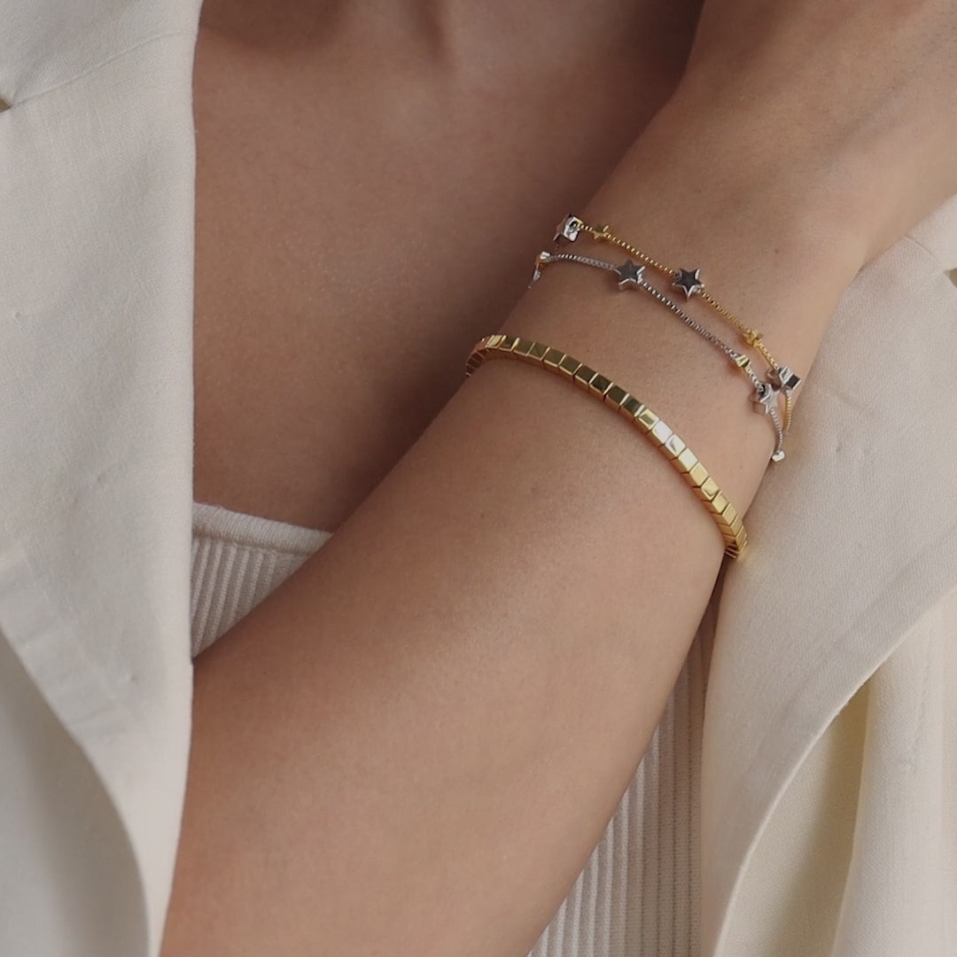 Model wearing Mixed Metal Star Bracelet, layered with a gold cube bracelet.