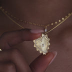 Model holds up a dainty chain with a dangling gold ribbed diamond heart charm on her neck