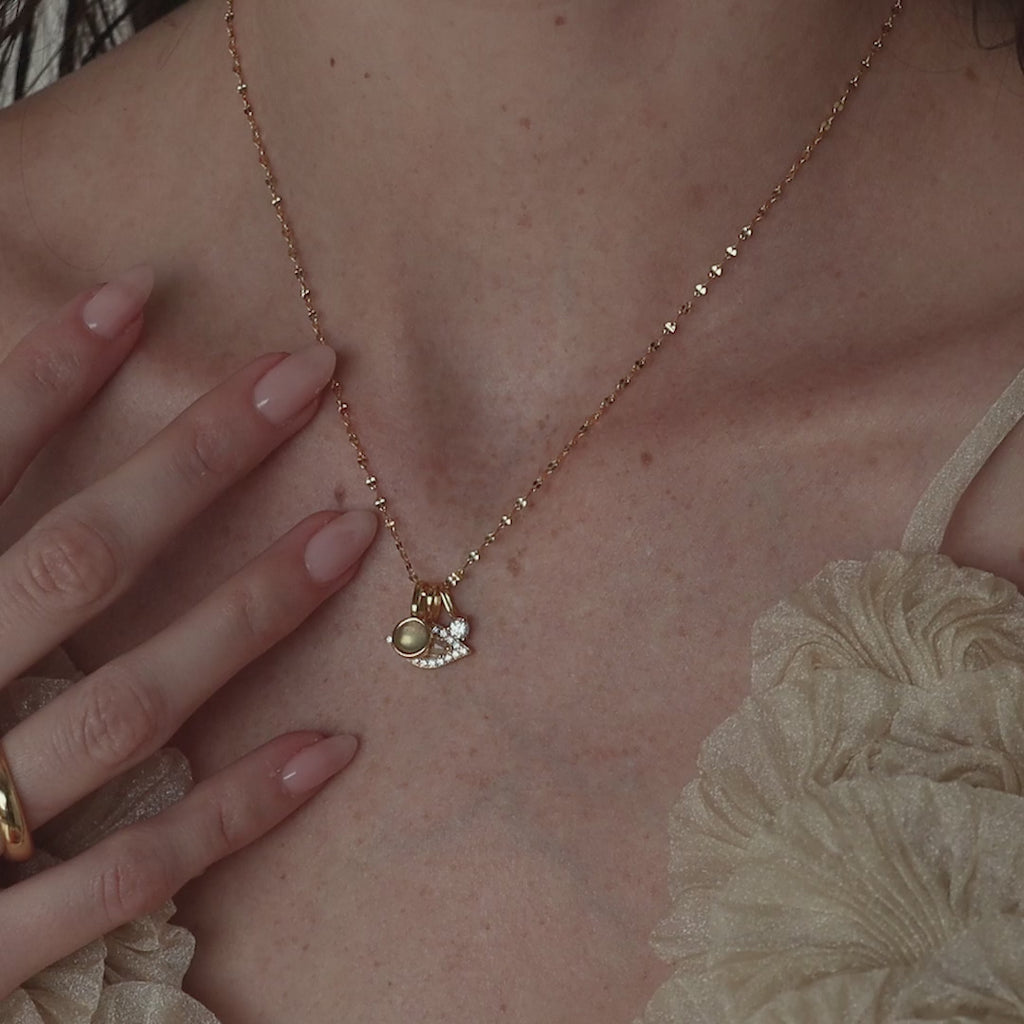 Model wears a mirror chain with a gold Pave Evil Eye Charm, moonstone signet charm and diamond birthstone charm