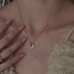 Model wears a mirror chain with a gold Pave Evil Eye Charm, moonstone signet charm and diamond birthstone charm
