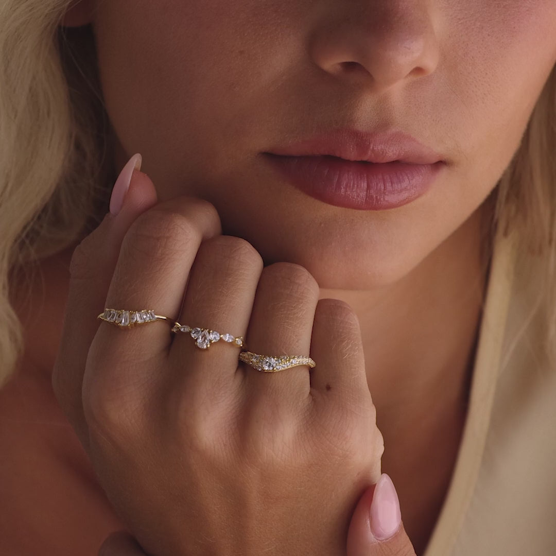 Model showcasing a gold pavé diamond ring with a curved band set with sparkling pavé diamonds, styled alongside two other gold diamond rings.