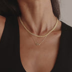 Layered gold chain necklaces styled on a woman, highlighting a minimalist snake pendant on the shortest chain.