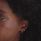 Close up of three dainty gold north star stud earrings with CZ diamond accents worn as a stack.