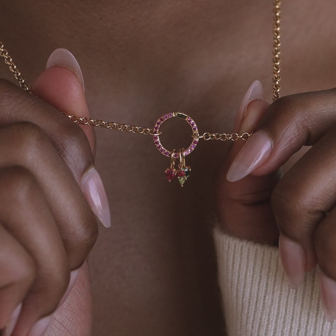 Model holds up a cable chain with a pave birthstone rolo clasp. The clasp has dangling birthstone charms on it