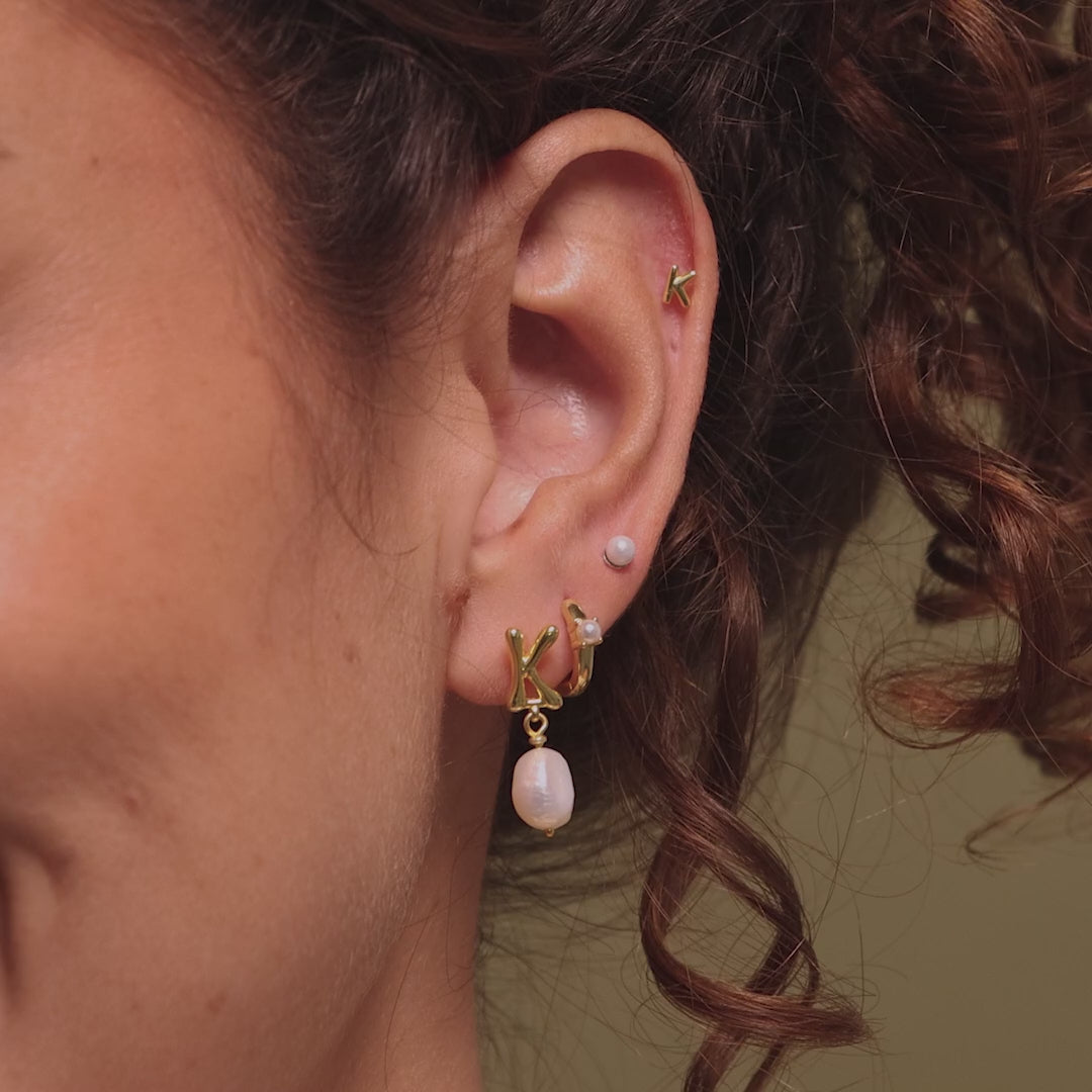 Video of a model wearing our Bubble Initial Flatback Studs, styled with our Initial Pearl Earrings and Pearl Studs