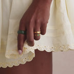 Model showcasing a thick green jade gemstone statement ring with a smooth, glossy finish, styled with two gold rings.