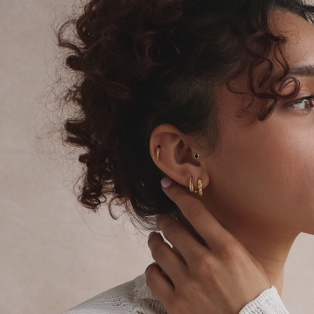 Model showcasing a curated stack of gold hoop and stud earrings.