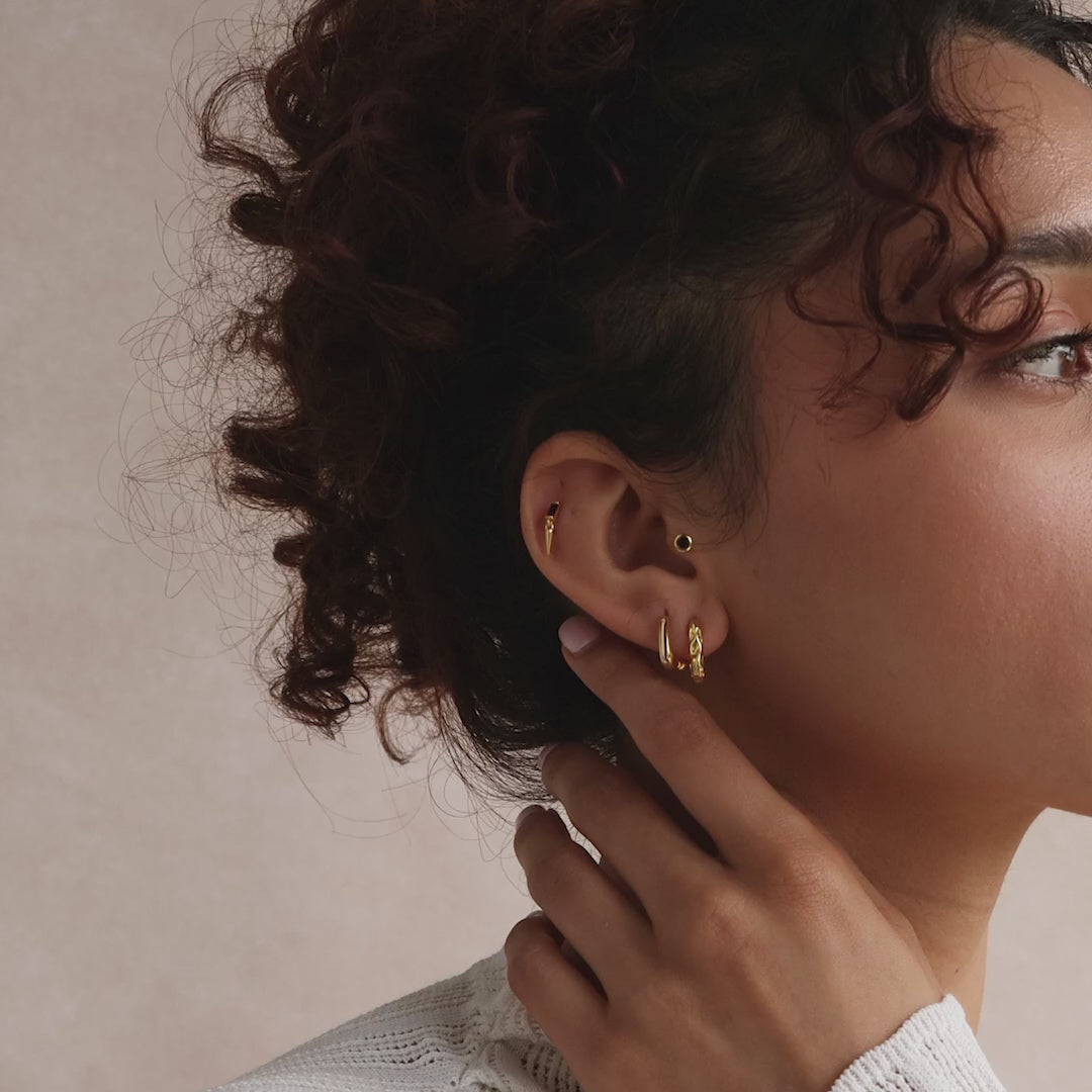 Model showcasing a curated stack of gold hoop and stud earrings.