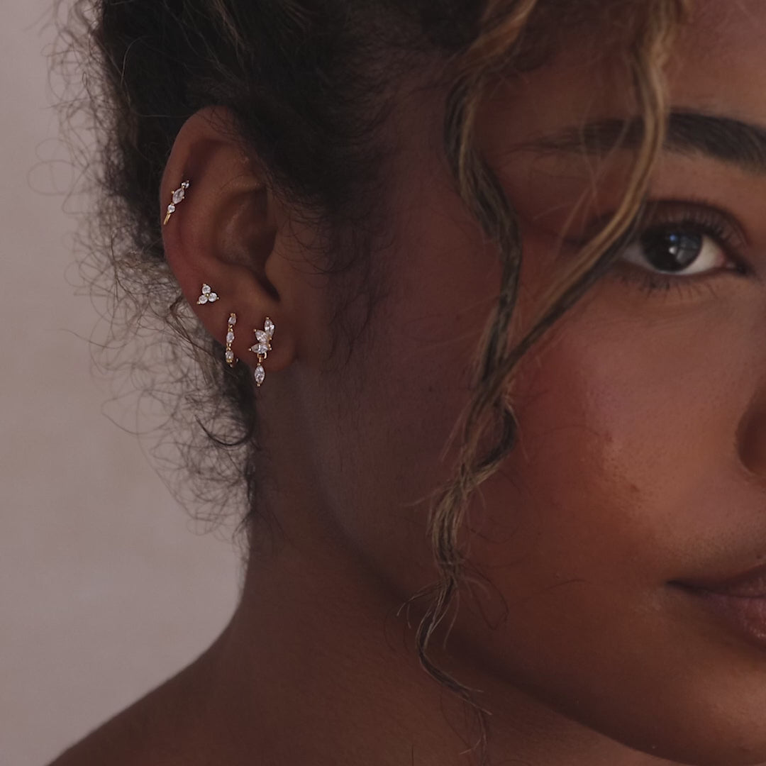 Model showcasing gold CZ diamond drop earrings with four marquise-cut stones, stacked with multiple gold earrings. 