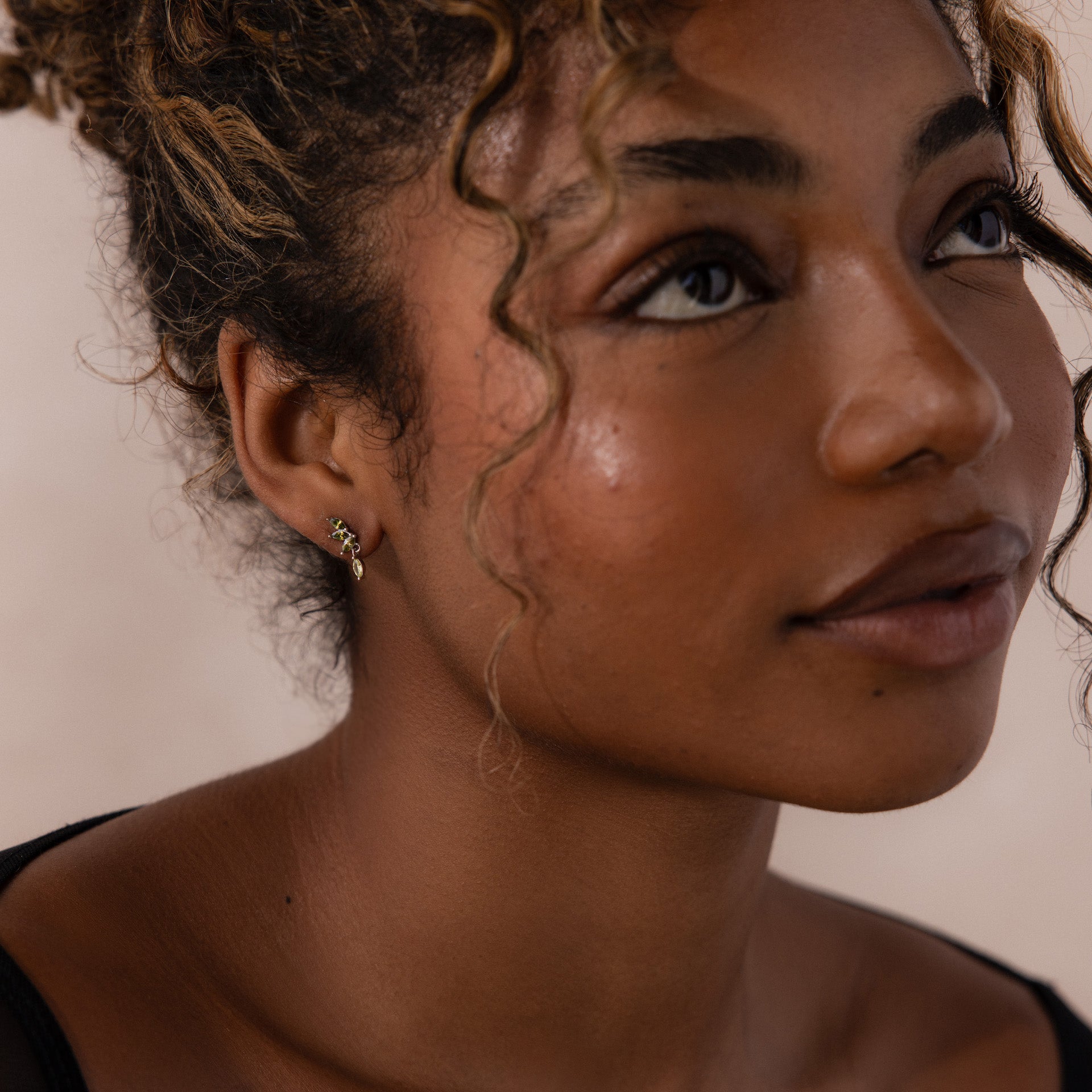 Model wearing silver marquise-cut drop earrings with green peridot gemstones arranged in a cascading leaf-inspired design.