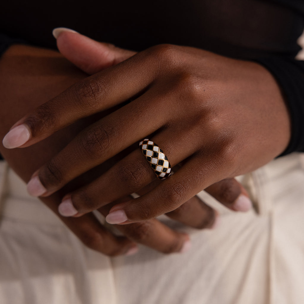 Model wearing a gold dome ring with black and white checkered enamel pattern.