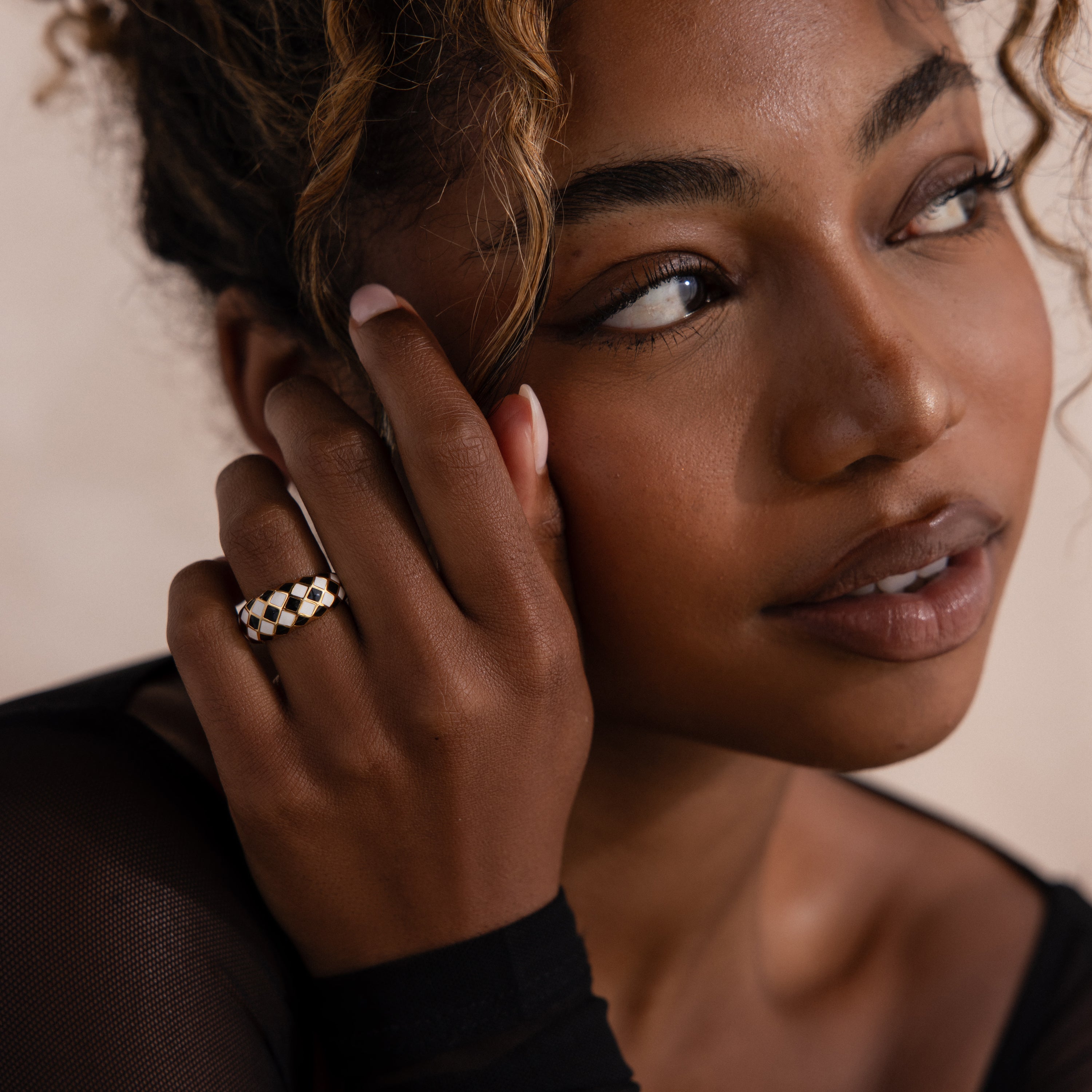 Model wearing a gold dome ring with black and white checkered enamel pattern.