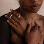 Model wearing a gold dome ring with black and white checkered enamel pattern, stacking with multiple gold rings.
