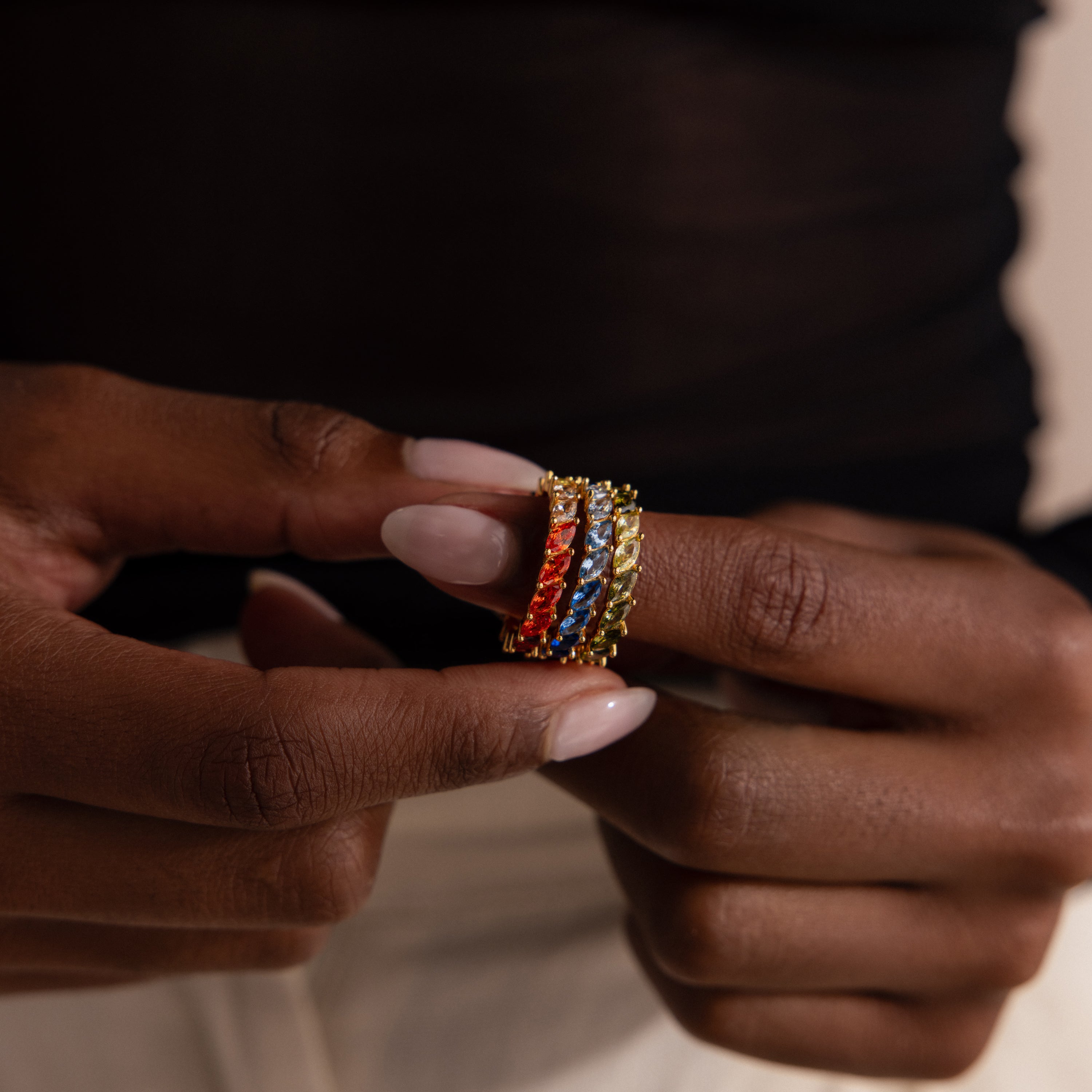 Close-up of hands holding colorful red, green and blue rings on a neutral background