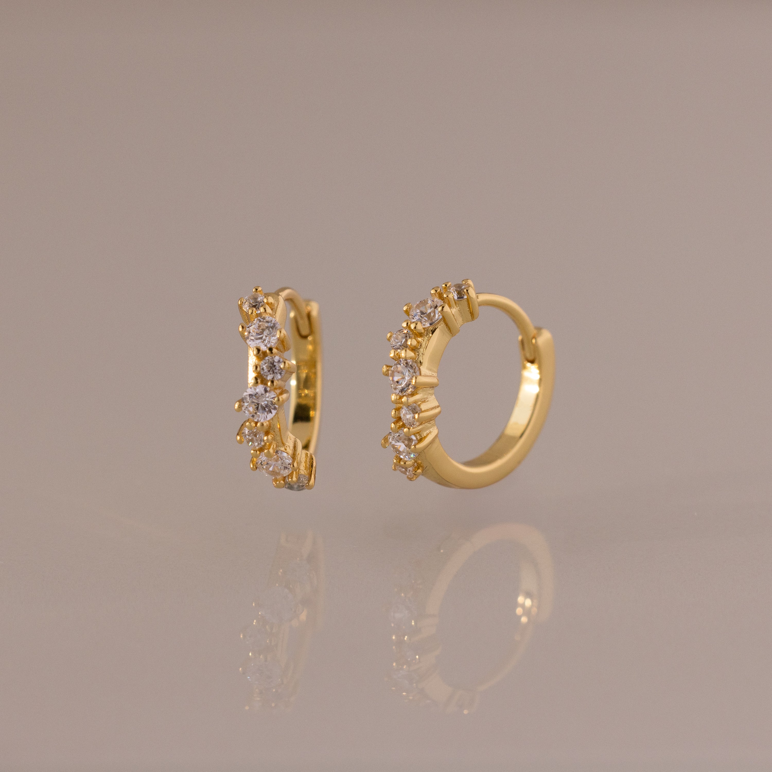 Marquise Cluster Hoop Earrings in gold with clustered CZ diamond stones, shown standing on a soft neutral surface.
