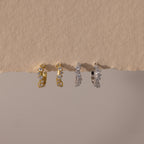 Two pairs of Marquise Cluster Hoop Earrings in gold and silver with clustered CZ diamond stones, displayed on a neutral surface.