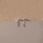 Marquise Cluster Hoop Earrings in silver with clustered CZ diamond stones, displayed on a neutral surface.